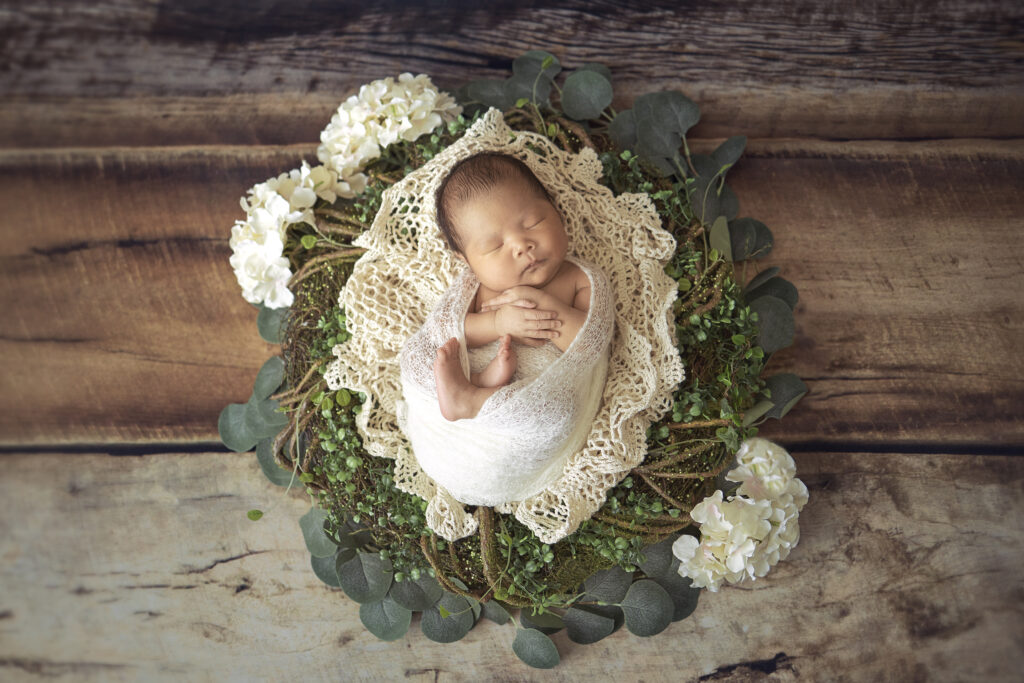 professional newborn photographer captures baby girl on mossy wreath
