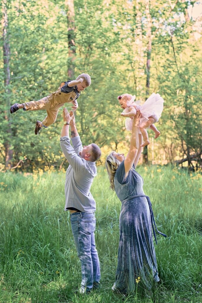 mother and father tossing two children up in the air and laughing