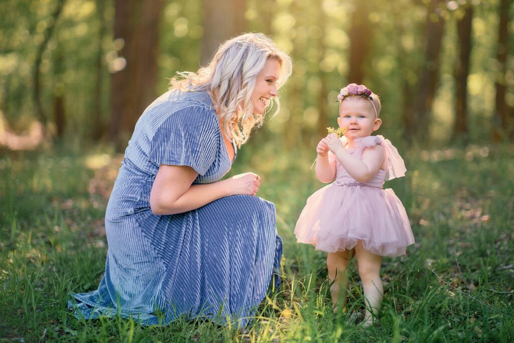 mother smiling at toddler daughter who is holding yellow flowers